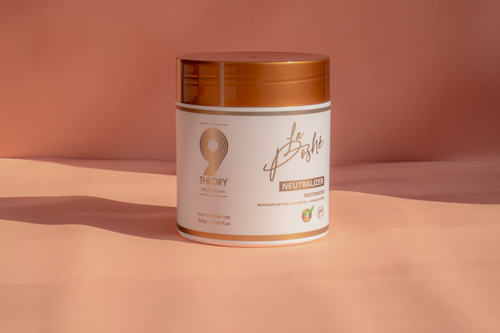 Jar of hair product with gold lid on a peach background