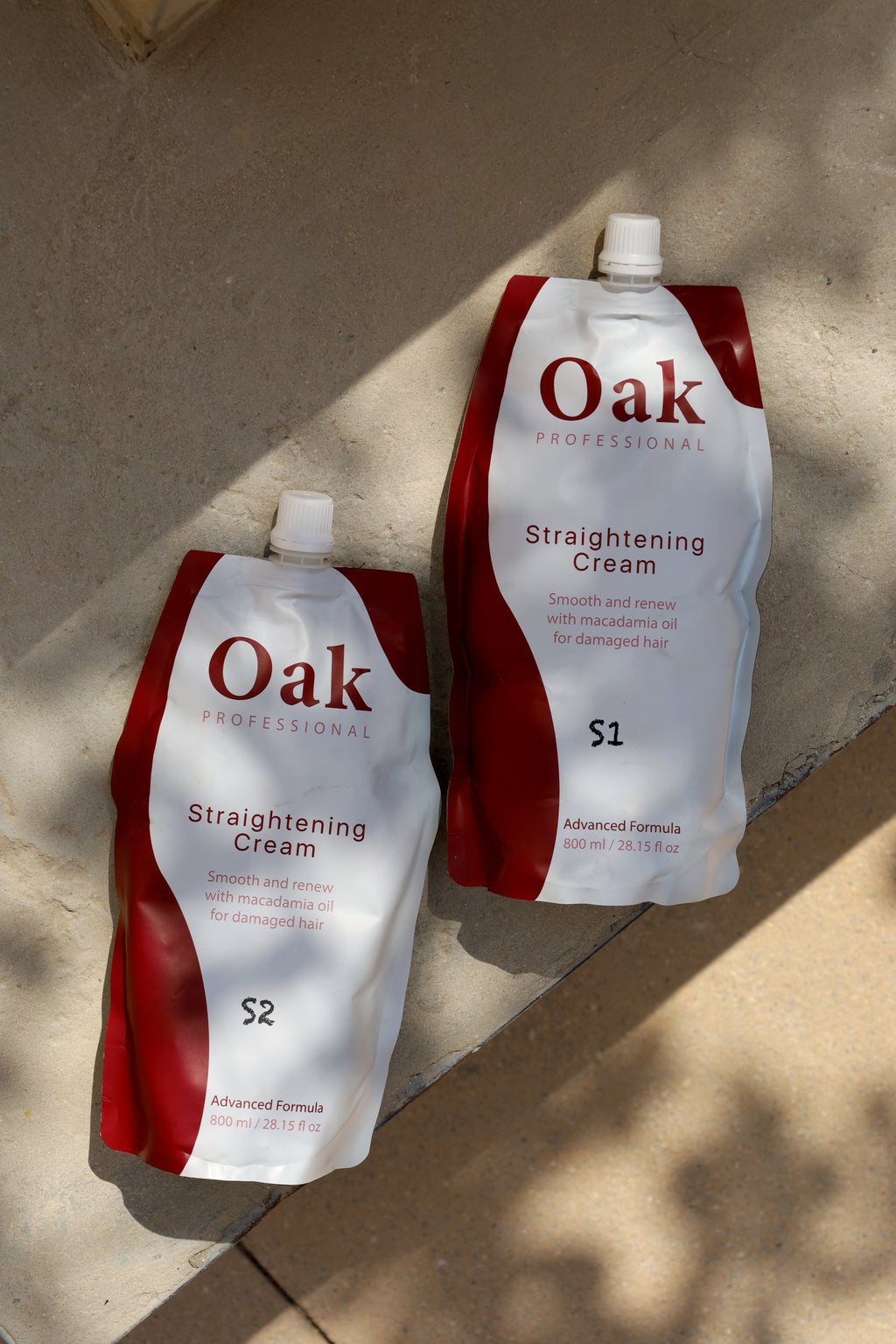 Two bottles of Oak Straightening Cream on a textured surface