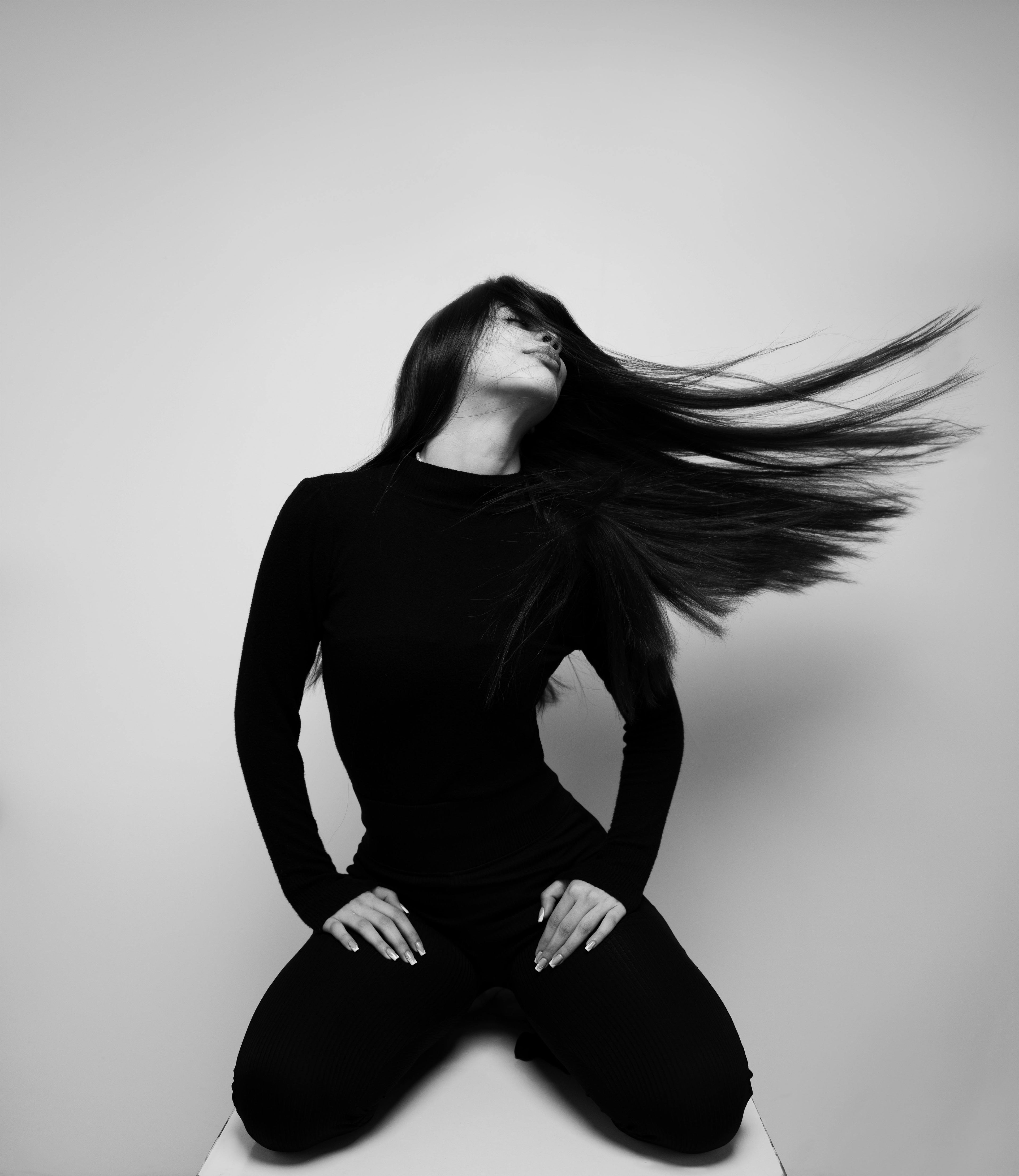 Person with long hair blowing in the wind against a plain background